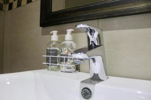 a bathroom sink with a faucet and two soap bottles at Cavallo Guesthouse in Windhoek