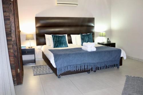 a bedroom with a large bed with a black headboard at Cavallo Guesthouse in Windhoek
