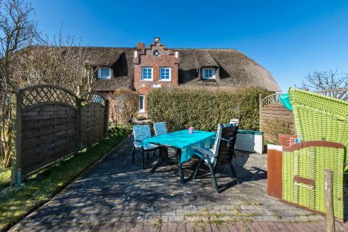 a patio with a table and chairs in front of a thatched house at Hus Tingeltut Gerd Clausen in Pellworm