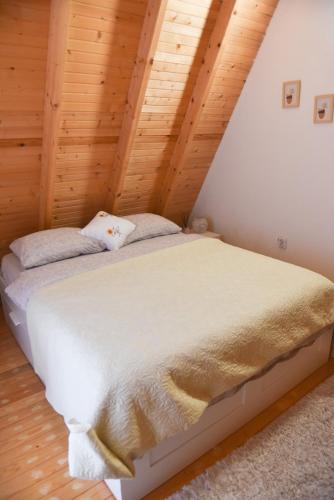 a bed in a room with a wooden ceiling at Sara in Malo Polje