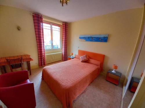 Un dormitorio con una cama y una silla y una ventana. en Villa Lutetia, en Le Mont-Dore
