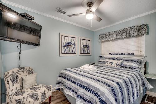 a bedroom with a bed and a tv and a chair at Drifty Daze Oceanfront Suite w Pool in Myrtle Beach