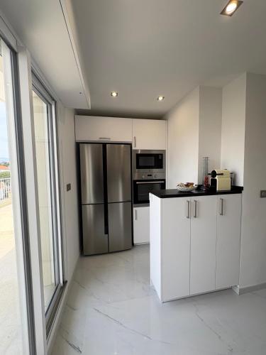 une cuisine avec des armoires blanches et un réfrigérateur en acier inoxydable dans l'établissement Cannes 2 suites 2 terrasses, à Cannes