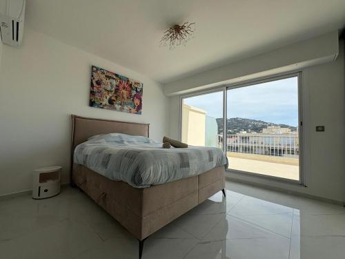 une chambre avec un lit et une grande fenêtre dans l'établissement Cannes 2 suites 2 terrasses, à Cannes