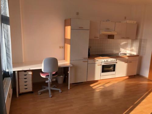 a small kitchen with a desk and a chair at helle 1Raum Wohnung Apartment mit Balkon und Küche in Dresden