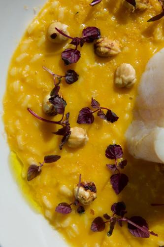 a bowl of yellow soup with flowers and nuts at Hôtel Val Chavière in Val Thorens