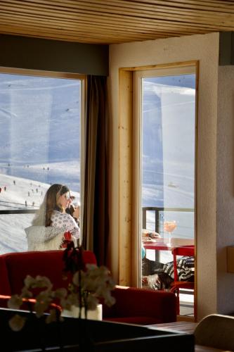 a woman is looking out a window at a beach at Hôtel Val Chavière in Val Thorens
