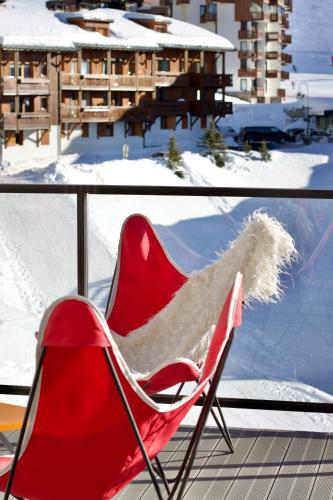 a red chair sitting on a balcony in the snow at Hôtel Val Chavière in Val Thorens