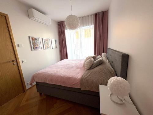 una camera da letto con un letto con lenzuola rosa e una finestra di Tiffany Residence a Pärnu