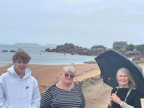un groupe de personnes debout sur une plage avec un parasol dans l'établissement Triagoz, à Trébeurden