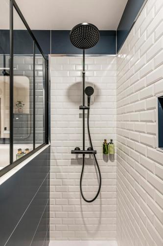La salle de bains est pourvue d'une douche et d'un mur en briques blanches. dans l'établissement CasaSol - Lyon PartDieu, à Lyon