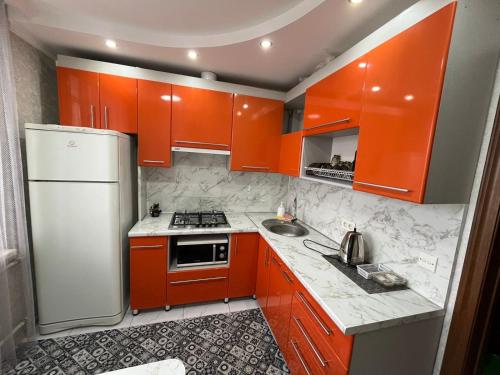 een keuken met oranje kasten en een witte koelkast bij Ермекова 52 in Karagandy