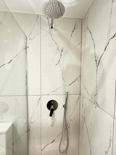 a bathroom with a shower with white marble walls at Voda apartments in Ksamil