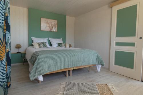 - une chambre dotée d'un lit avec un mur vert dans l'établissement La Grange, à Cléder