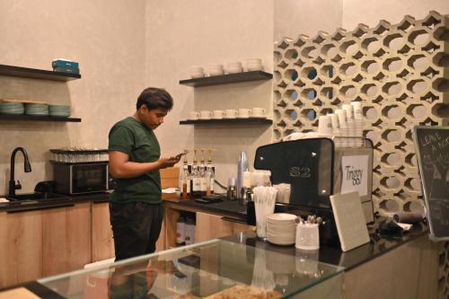 a man standing in a kitchen looking at his cell phone at LOKAL Flagship x Karachi - DHA in Karachi
