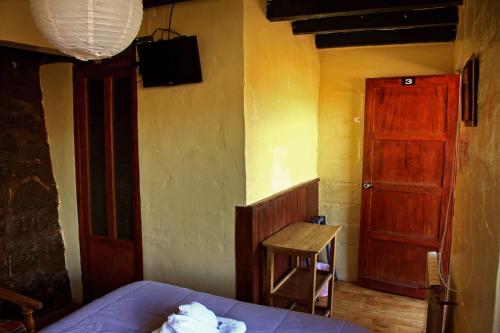 a bedroom with a bed and a red door and a stool at Samay Wasi Hostel in Cusco