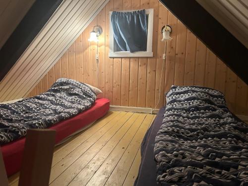 トロムソにあるSjursnes, Lyngen alps, Aurora borealisのベッド2台と窓が備わる屋根裏部屋です。