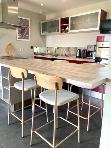 une cuisine avec un comptoir en bois et quatre tabourets dans l'établissement Appart à 200m de la plage de Contis, à Saint-Julien-en-Born