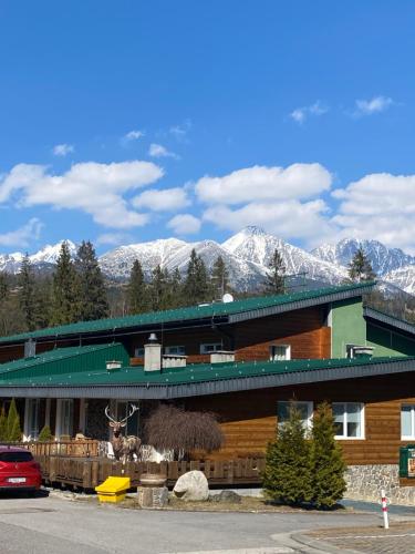 a building with snow covered mountains in the background at Apartmán DEJA VÚ - Tatranská Štrba in Štrba