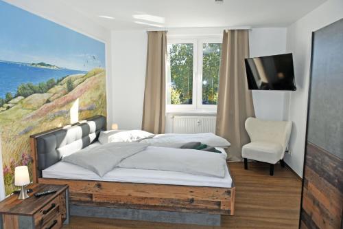 a bedroom with a bed and a tv and a chair at Baaber Hotel mit Frühstück in Baabe