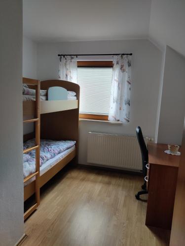 a bedroom with bunk beds and a desk and a window at Countryside house in Male Brusnice