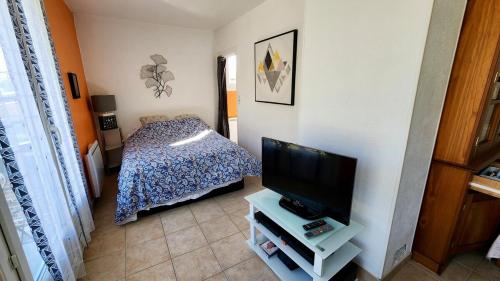 Un dormitorio con una cama y un televisor de pantalla plana. en Laurence's Home, en Veules-les-Roses