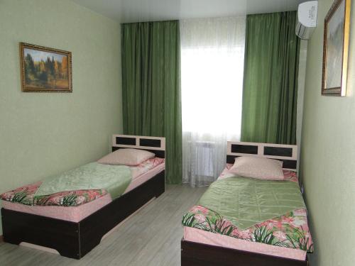 ハバロフスクにあるApartment Sokolniki Plusの緑のカーテンと窓が備わる客室で、ベッド2台が備わります。