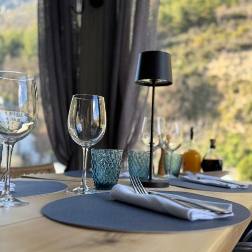a table with wine glasses and a lamp on it at Hôtel Fleur des Alpes in La Brigue