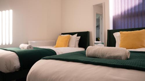 a room with three beds with green and yellow pillows at Prestige Stays Cardiff Modern 2-Bedroom Duplex Apartment near City Centre Wi-Fi & Lockbox Check-In in Cardiff