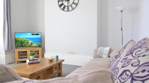 a living room with a couch and a tv at Spacious Penthouse in Central Plymouth 3 Large Bedrooms in Plymouth