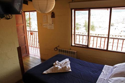 a bedroom with a blue bed and two windows at Samay Wasi Hostel in Cusco