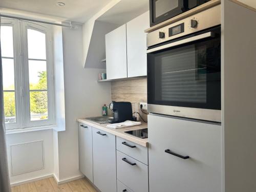 une cuisine avec des armoires blanches et un micro-ondes dans l'établissement Ile de groix - T2 - centre-ville - TV, à Vannes