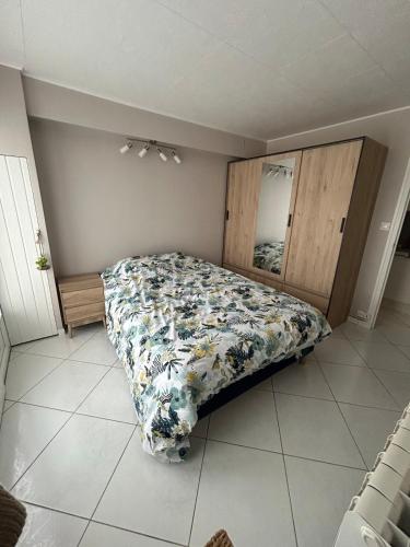 une chambre avec un lit avec une couette fleurie dans l'établissement Charmant logement tout équipé à 150m de la plage, à Saint-Pair-sur-Mer