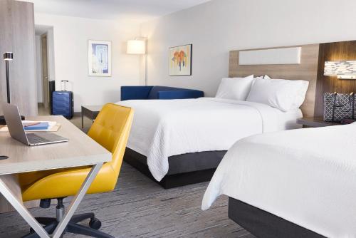 a hotel room with two beds and a desk and a laptop at Holiday Inn Express & Suites Colby in Colby