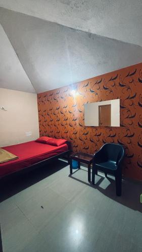 a bedroom with a red bed and a black chair at AURA PARK STAY - Kumta in Kumta