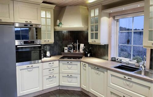 a kitchen with white cabinets and a sink and a window at Beautiful Home In Charlottenberg in Charlottenberg