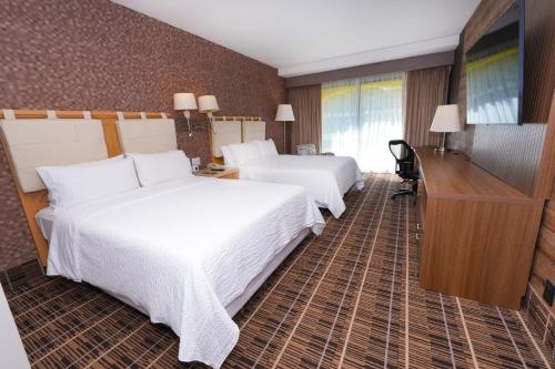 a hotel room with two beds and a television at Holiday Inn Queretaro Centro Historico by IHG in Querétaro