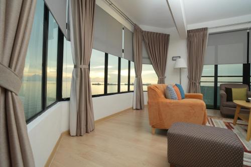 a living room with a couch and large windows at Twynstar Mutiara Melaka Beach Resort in Tangga Batu