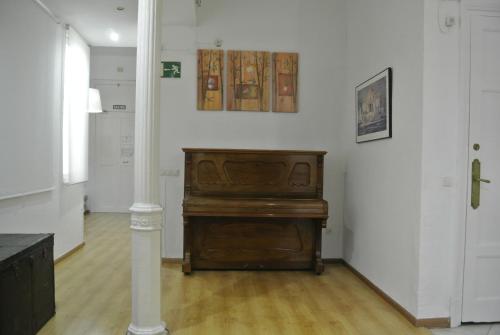 a piano in a room with a white wall at Pensión Santa Paula in Málaga