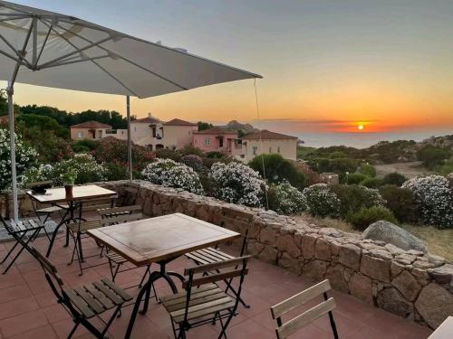 a patio with tables and chairs and a sunset at Il Rumore del Mare Beach House in Trinità dʼAgultu