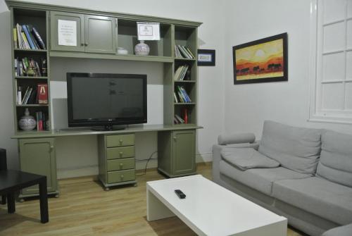 a living room with a couch and a flat screen tv at Pensión Santa Paula in Málaga