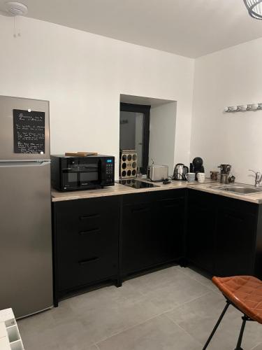 La cuisine est équipée de placards noirs, d'un four micro-ondes et d'un réfrigérateur. dans l'établissement love aphrodite, à Bubry