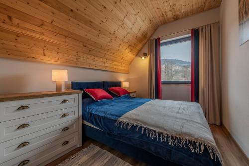 a bedroom with a bed with blue sheets and red pillows at Osada Niebieskich Drzwi in Stronie Śląskie