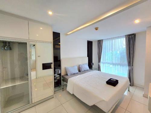 1 dormitorio con cama blanca y pared de cristal en City Center Residence NEW, en Pattaya central