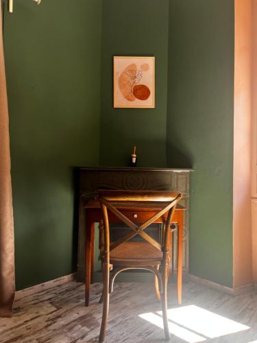 a table and a chair next to a green wall at Hôtel Fleur des Alpes in La Brigue