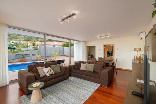 a living room with two couches and a large window at Private pool and sea view - Tropical Villa in Arco da Calheta