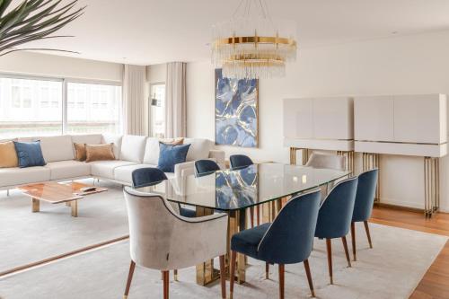 a living room with a glass table and blue chairs at The Eight Luxury Stay in Penafiel