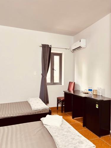 a room with two beds and a desk and a window at Ruby Căn hộ Dịch vụ Khách sạn in Ga Phú Văn