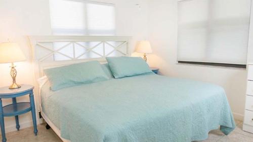 a bedroom with a bed with blue sheets and two tables at Stylish Beachside Retreat on Sanibel Island in Sanibel