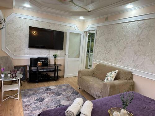 a living room with a couch and a tv on a wall at Уютный уголок in Shymkent